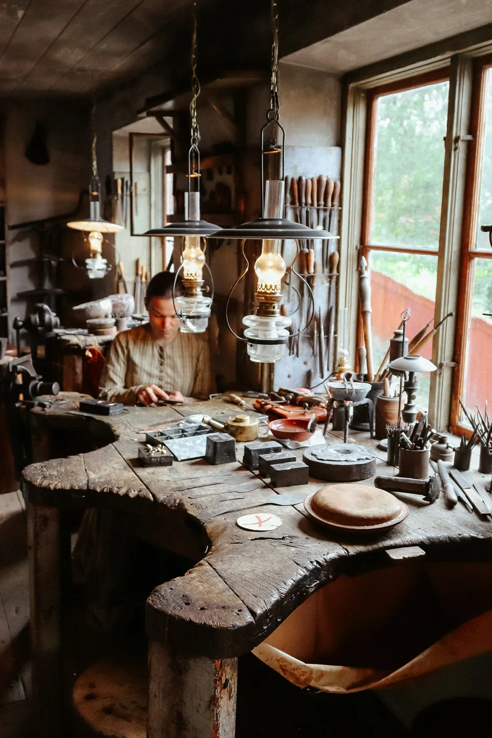 A craftsperson at work beside a window in a traditional workshop